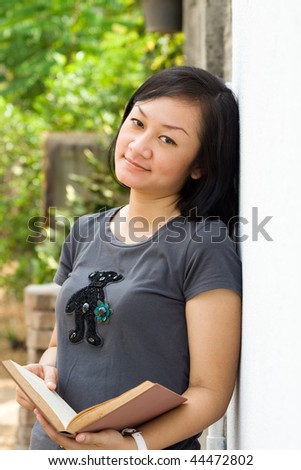 portrait of asian female university student with open books on hands