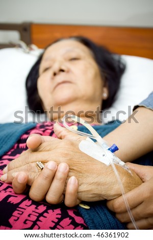 holding hands as for mental support to the sick people. grandma hand being hold by her daughter