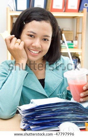 asian ethnic business woman eat snack and drink while at work in the office
