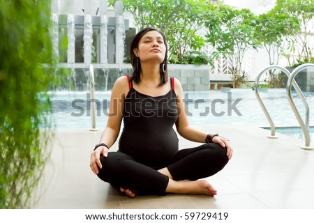 Asian ethnic pregnant woman doing breathing exercise by the pool