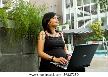 Asian pregnant business woman happy working with laptop
