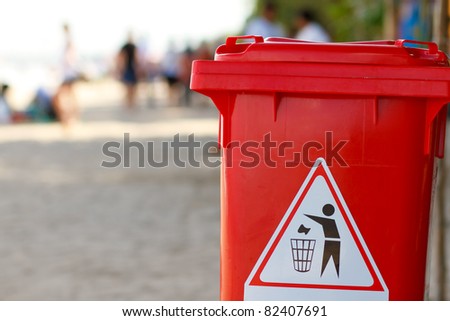 clean red plastic trash bin on the beach