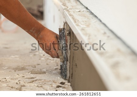 Man hand with trowel plastering a foundation of house