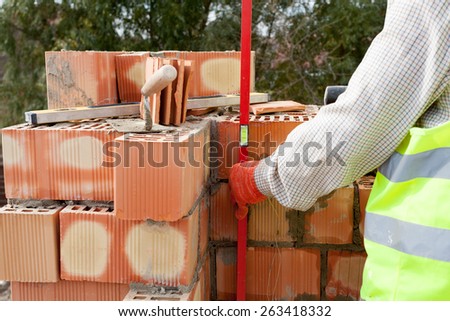 Construction mason worker measuring with professional level the bricks on walls
