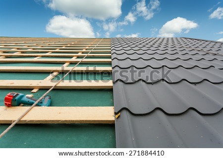 House under construction.Roof  with metal tile,screwdriver and roofing iron