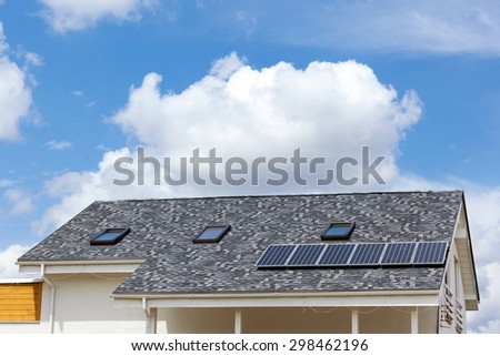 Solar water panel heating on new house roof with skylights against blue sky