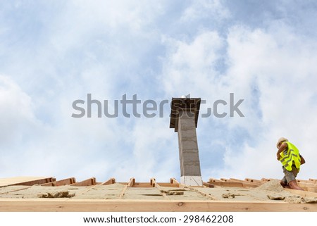 Construction crew working on the roof with chimney against blue sky