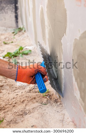 Construction worker plastering a wall  and house foundation with trowel