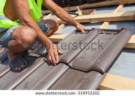 Hands of roofer laying tile on the roof. Installing natural red tile.