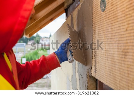 Worker plastering a facade of a new house on mineral rockwool panels. Process of insulation of house for better energy efficiency
