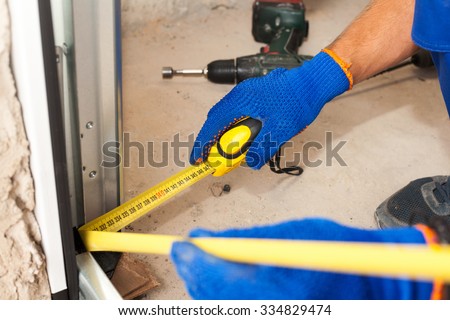 Garage Door Installation. Worker use a ruler to verify correct installation of metal profile