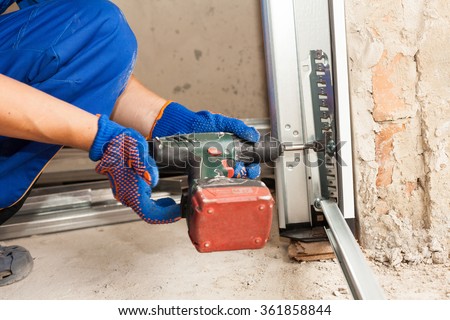 Garage doors installation. Worker use automatic screwdriver  to fix a bolt
