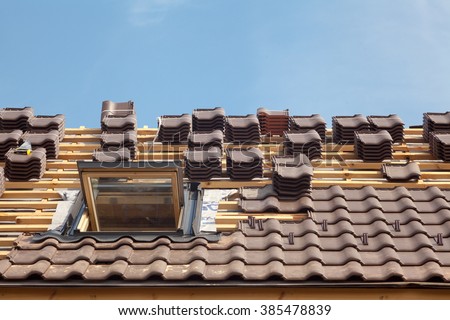 House under construction. Roofing tiles with open skylight