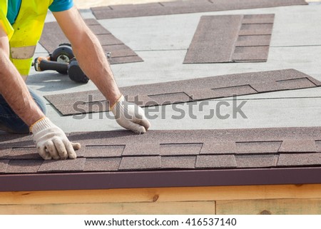 Roofer builder worker installing roof shingles