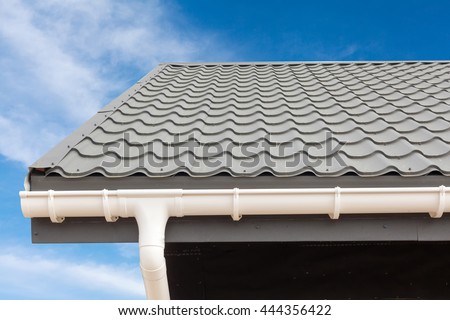 SIP panel house construction. New gray metal tile roof with white rain gutter