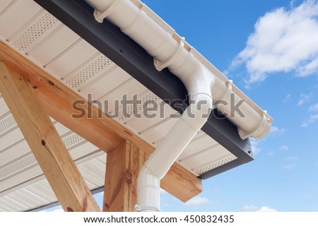 SIP panel house construction. New white rain gutter.  Drainage System with Plastic Siding Soffits and Eaves against blue sky