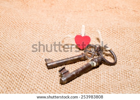 Two vintage key and a red wooden heart on old cloth