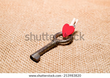 One vintage key and a red wooden heart on old cloth