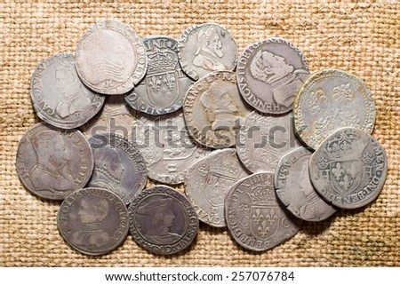 A lot of old silver coins with portraits of kings on the old cloth
