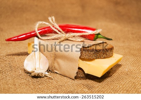 Sandwich with cheese wrapped in paper, chili pepper and garlic on old cloth