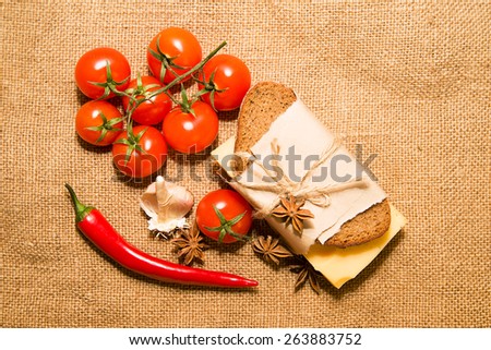 Sandwich with cheese wrapped in paper,chili pepper, cherry tomatoes and garlic on cloth