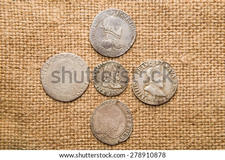 A lot of old  coins with portraits of kings on the old cloth