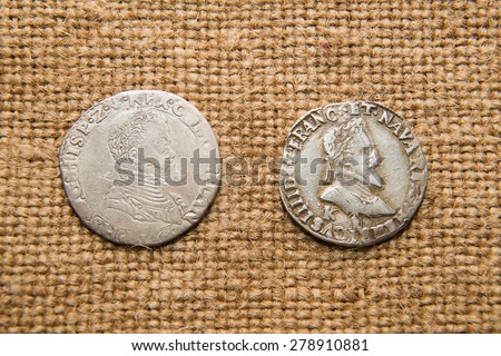 A lot of old  coins with portraits of kings on the old cloth