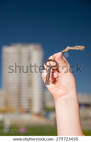 Child hand holding an old keys on a string against the sky