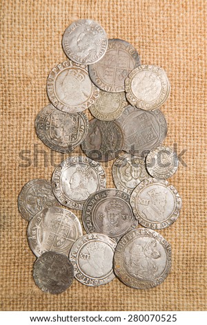A lot of old silver coins with portraits of kings on the old cloth