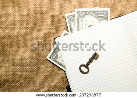 Opened notebook with a blank sheet, key and money on the old tissue