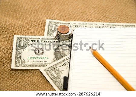 Opened notebook with a blank sheet, pencil and money on the old tissue