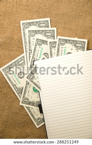 Opened notebook with a blank sheet and money on the old tissue