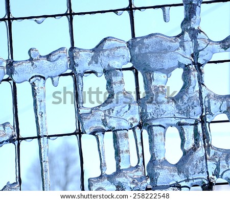 Frozen water drips on the fence.