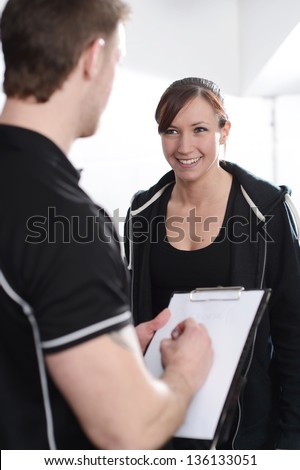 Fitness Instructor interviewing new client in gym
