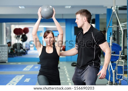 Personal Trainer Helping Young Woman In Gym