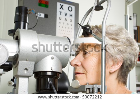An older lady taking an eyesight test examination at an optician clinic
