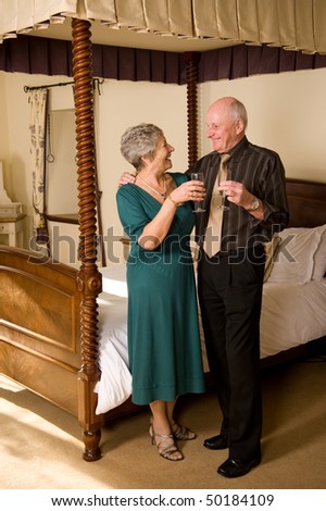 Romantic senior older couple celebrating in beautiful hotel suite