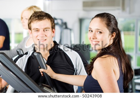 Personal trainers in the gym giving instruction and help to attractive young women