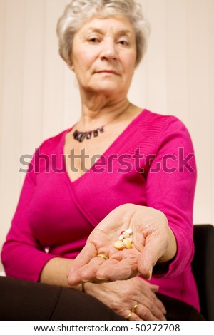 Senior older woman holding a selection of tablets or pills in her hand
