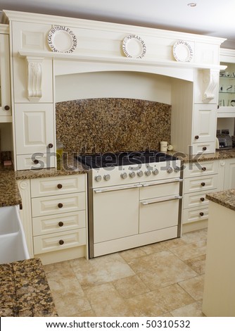 Range style cooker in a modern kitchen interior with granite worktop and cream units