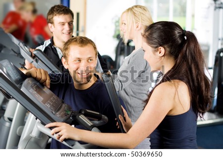 Personal trainers in the gym giving instruction and help to attractive young women