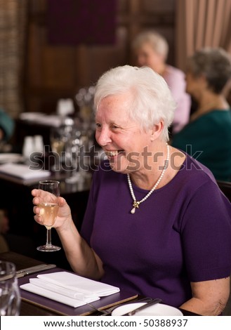Older mature senior lady celebrating in posh restaurant