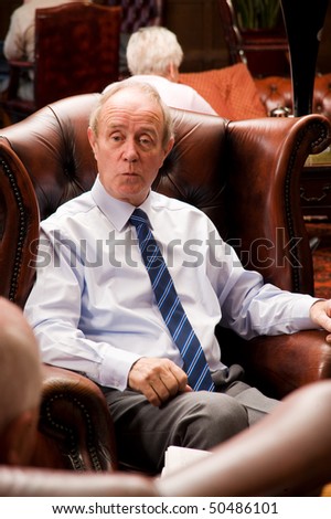 Senior older man talking with friends in luxurious hotel lounge