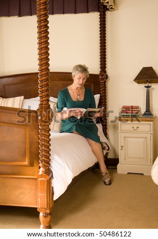 Senior older lady reading magazine in luxurious hotel bedroom
