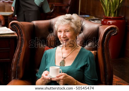 A mature older lady enjoying tea and talking with friends