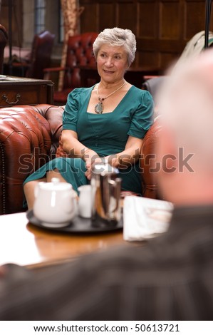 A mature older lady enjoying tea and talking with friends