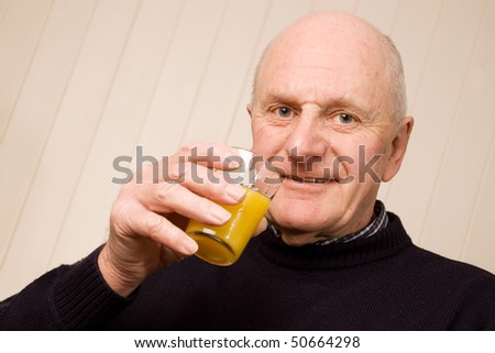 Happy senior older man holding a glass of fresh orange juice