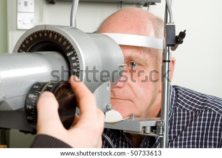 An older man taking an eye test examination at an opticians clinic