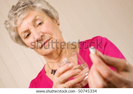 stock photo Senior mature lady holding a tablet or pill in one hand and a