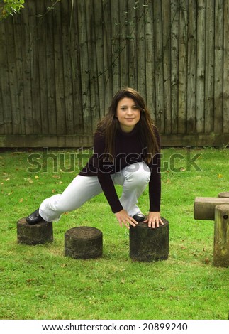 Woman climbing over stepping stones in the playground.